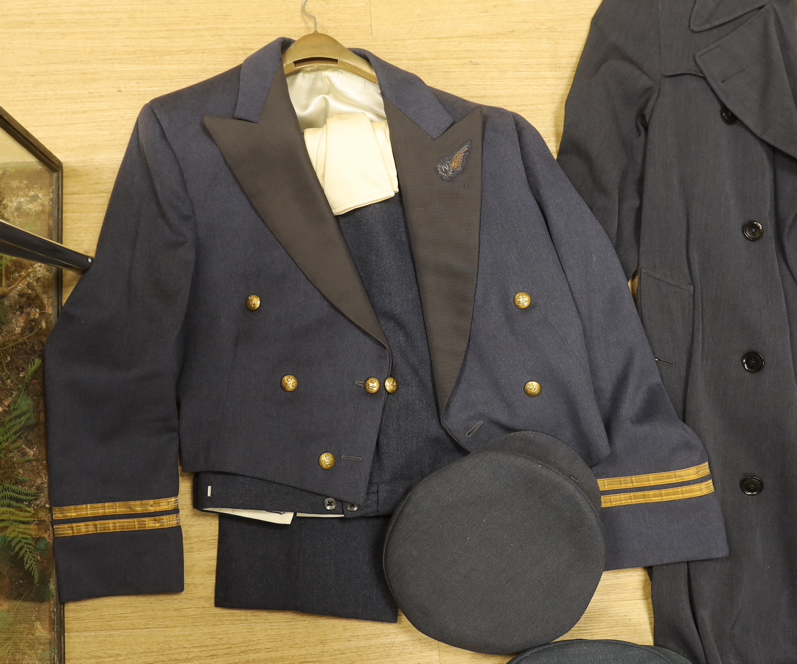 A collection of post-war RAF uniforms, comprising; two caps, double-breasted overcoat, dress uniform of jacket, trousers and gloves, two sets of jacket and trousers with ribbons for WWII awards, plus a pair of navigator’